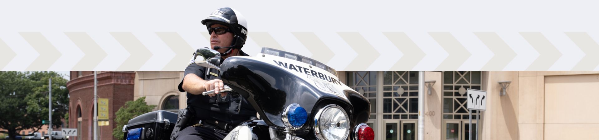 A Waterbury police officer riding a motorcycle through a downtown area