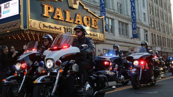 A group of Waterbury police motorcycles riding in a procession past the Palace Theater