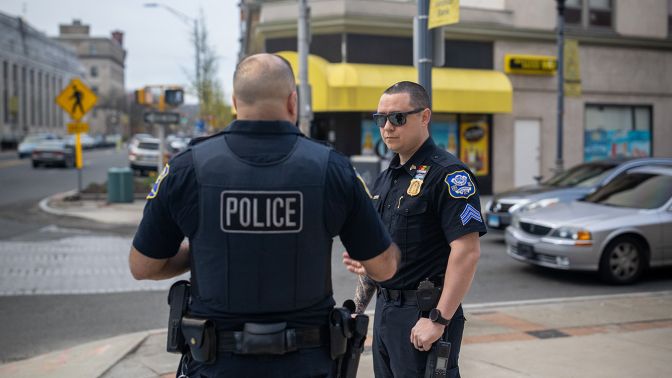 Two Waterbury police officers having a discussion on a city sidewalk